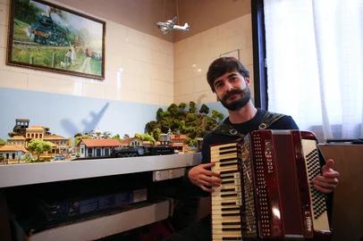 Ariéli Ziegler / Agencia RBS CAXIAS DO SUL, RS, BRASIL, 20/05/2026. O acordeonista caxiense Gabriel Zuccoloto Ramos, morador de Forqueta, une as paixões pela música e pelos trens trabalhando como músico nos vagões do trem turístico Maria Fumaça. Ele também é colecionador de acordeons raros, italianos e nacionais, e ferromodelismo.(Ariéli Ziegler/Agência RBS)Indexador: Arieli Ziegler<!-- NICAID(16289501) -->
