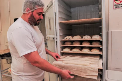 CAXIAS DO SUL, RS, BRASIL, 06/07/2023. Rodrigo Gomes, 45 anos, é o padeiro e fundador da Pane & Salute Padaria Artesanal que funciona há 10 anos em Caxias do Sul e tem hoje duas lojas na cidade. Na matriz, onde é realizada toda a produção, são 20 colaboradores, sendo cinco envolvidos diretamente com a elaboração dos pães artesanais. O estabelecimento foi o primeiro emprego de Robert Jean, 44 anos, no Brasil. O haitiano que morava na República Dominicana chegou a Caxias do Sul buscando melhores condições de vida e por meio da panificação comprou uma casa e pôde trazer seus familaires ao país onde está radicado. (Neimar De Cesero/Agência RBS)Indexador: NEIMAR DE CESERO<!-- NICAID(15475998) -->