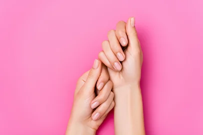 top view of female hands with pastel nail varnish on fingernails on pink backgroundFonte: 404512832<!-- NICAID(16164433) -->