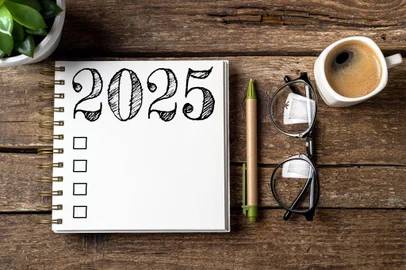 New year resolutions 2025 on desk. 2025 resolutions list with notebook, coffee cup on table. Goals, resolutions, plan, action, checklist concept. New Year 2025 template, copy space<!-- NICAID(15944646) -->