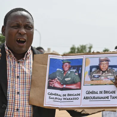 A supporter of Niger's National Council for the Safeguard of the Homeland (CNSP) holds up a placeard with a photo of General Abdourahamane Tiani on in Niamey on August 6, 2023. Thousands of supporters of the military coup in Niger gathered at a Niamey stadium Sunday, when a deadline set by the West African regional bloc ECOWAS to return the deposed President Mohamed Bazoum to power is set to expire, according to AFP journalists. A delegation of members of the ruling National Council for the Safeguard of the Homeland (CNSP) arrived at the 30,000-seat stadium to cheers from supporters, many of whom were drapped in Russian flags and portraits of CNSP leaders. (Photo by AFP)<!-- NICAID(15506432) -->
