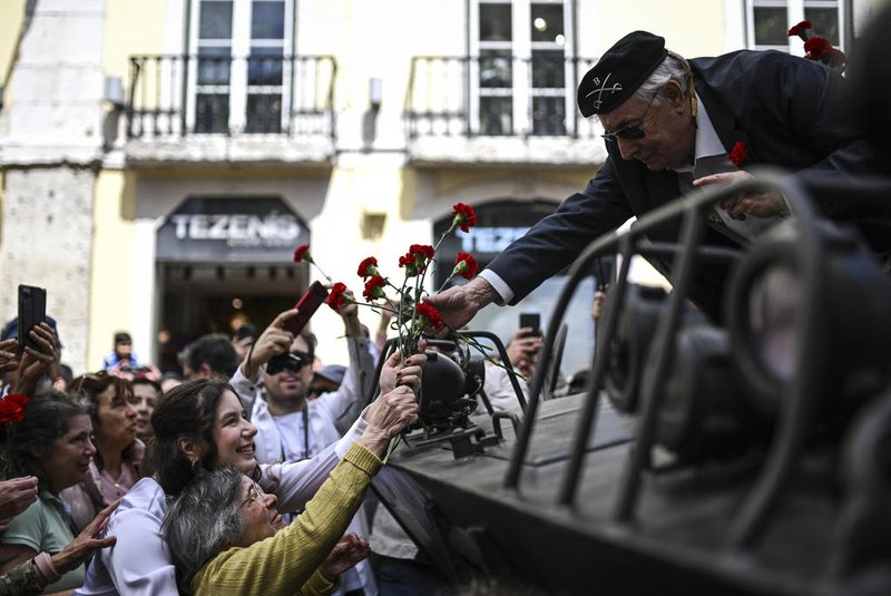 90 years old Celeste Caeiro (R), who handed red carnations to the military taking part in the Portuguese revolution on April 25, 1974, gives a bouquet of carnations to a former soldier during a military parade to celebrate the Carnation Revolutions 50th anniversary in Lisbon on April 25, 2024. Portugal marks the 50th anniversary of the Carnation Revolution, a military coup that put an end to Europe's longest-lived dictatorship and 13 years of colonial wars in Africa. (Photo by PATRICIA DE MELO MOREIRA / AFP)<!-- NICAID(15744849) -->
