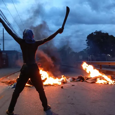 A protester holds a machete as he gestures next to a burning barricade in Maputo on December 23, 2024. Mozambique's highest court confirmed Monday the ruling party's victory in a disputed October vote after allegations of rigging triggered weeks of deadly street clashes. Fears are high that more violence could break out in the southern African nation after the opposition threatened to call an uprising following the decision. (Photo by Amilton Neves / AFP)<!-- NICAID(15941513) -->