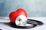 Stethoscope, red heart and cardiogram on table. Cardiology conceptFonte: 246669825<!-- NICAID(15240842) -->