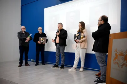 Ricardo Rech / Divulgação Embaixadores do Turismo de Caxias do Sul 2026/2027 ( da esquerda para a direita): Ubiratã Rezler, presidente da CIC Caxias, Ronei Tonet, guia de turismo, e Paola Benevenuto, assessora de turismo da Sicredi Pioneira. Ao centro, com o microfone, vice-prefeito Edson Néspolo. No canto, de jaqueta preta, secretário de Turismo e Desemvolvimento Econômico, Felipe Gremelmaier. <!-- NICAID(16361181) -->