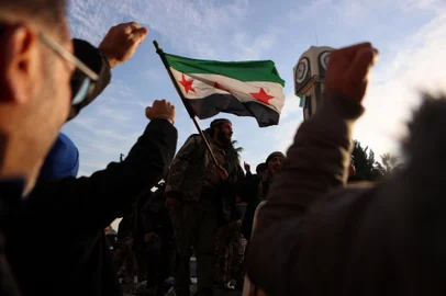 Syrian rebel fighters celebrate at the Clock Tower in the heart of the central city of Homs early on December 8, 2024, after rebel forces entered Syria's third city overnight. Hayat Tahrir al-Sham (HTS) and allied anti-goovernment factions have pressed a lightning offensive since November 27, sweeping swathes of the country from government control, including major cities Aleppo, Hama and Homs. (Photo by Aaref WATAD / AFP)<!-- NICAID(15930926) -->