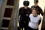 A handout picture taken on November 19, 2013 and released by Greenpeace International shows Greenpeace International activist, one of the "Arctic 30," Ana Paula Alminhana Maciel from Brazil (R), smiling while being escorted by police officers in a court in Russia's second city of Saint Petersburg. A Russian court released on bail the Brazilian Greenpeace activist, the first non-Russian to be set free from the so-called Arctic 30 detained for a protest against oil drilling, the group said today. AFP PHOTO / GREENPEACE DMITRI SHAROMOV
---EDITORS NOTE-- IMAGE AVAILABLE FOR DOWNLOAD BY EXTERNAL MEDIA FOR 14 DAYS AFTER RELEASE -- RESTRICTED TO EDITORIAL USE - MANDATORY CREDIT "AFP PHOTO / GREENPEACE /DMITRI SHAROMOV" - NO MARKETING NO ADVERTISING CAMPAIGNS - DISTRIBUTED AS A SERVICE TO CLIENTS --  NO ARCHIVE -----