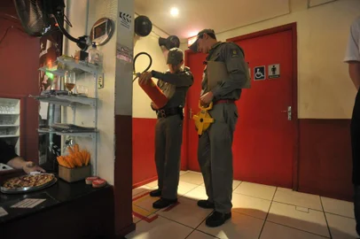  O Diário acompanhou as equipes de fiscalização em três dos 14 bares, boates e restaurantes visitados na noite de terça-feira. Do total, 12 foram inspecionadas e duas estavam fechadas. Participaram da ação cinco fiscais do Conselho Regional de Engenharia e Agronomia (Crea) e quatro bombeiros da Seção de Prevenção a Incêndios (SPI). A prefeitura que também participaria da ação, não foi. Do total, cinco apresentavam algum tipo de irregularidade em relação ao Plano de Prevenção Contra Incêndios (PPCI) _ três foram notificados para fazerem correções e dois advertidos. Todos receberam prazos entre 30 e 60 dias para se adequarem. Por parte do Crea, a todos os estabelecimentos foi entregue um pedido para apresentem 11 tipos de laudos, com Anotações de Responsabilidade Técnica (ARTs) no prazo de 10 dias. Cada local, tem de entregar os documentos correspondentes a sua atividade. Na foto: Bar Ponto de Cinema.