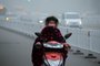 A woman rides a scooter down a polluted street while wearing a face mask in Bozhou, in eastern China's Anhui province on December 24, 2015. Ten Chinese cities were on red alert for smog on December 24, state media reported, as large swathes of the country suffered through their fourth wave of choking pollution this month.     CHINA OUT     AFP PHOTO / AFP / STR