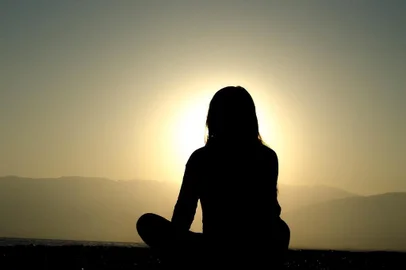 Mulher medita de frente para o sol. Saiba quais os benefícios que a meditação traz para a saúde. CADERNO VIDA. 29/04/2016.