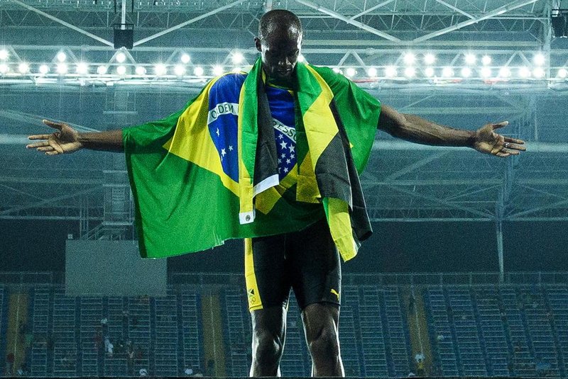 Jamaica's Usain Bolt poses with the Jamaican flag after Team Jamaica won the Men's 4x100m Relay Final during the athletics event at the Rio 2016 Olympic Games at the Olympic Stadium in Rio de Janeiro on August 19, 2016. / AFP PHOTO / LEON NEAL