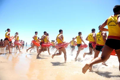 Uma simulação de salvamento no mar chamou a atenção de veranistas em Tramandaí, no Litoral Norte, no fim da manhã desta terça-feira. O exercício, que contou com um helicóptero do Grupamento Aéreo da Brigada Militar, marcou o Dia do Salva-Vidas e levou dezenas de pessoas para a beira da praia.O treinamento começou por volta das 11h40min, em frente à guarita 146, depois de uma cerimônia de formatura e de uma competição envolvendo corrida e natação. Um socorrista entrou no mar e representou o papel de vítima de afogamento. Em seguida, tiveram início os exercícios, com jet sky e helicóptero. A ação arrancou aplausos dos veranistas.