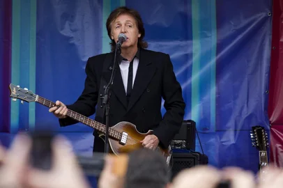 British musician Paul McCartney (C) performs during an impromptu gig in Covent Garden in London on October 18, 2013.  Paul McCartney played a surprise gig at Londons Covent Garden, drawing a crowd of hundreds as he and a band performed half a dozen songs from the back of a truck. The 71-year-old former Beatle played a colourful piano and strummed the guitar in a stunt to promote New, his first album of solo material in six years.