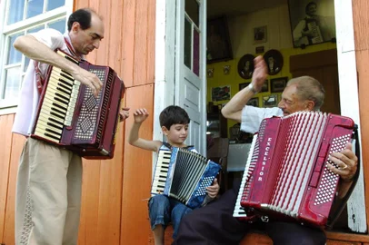  Adelar Bertussi, em sua propriedade na localidade de Criuva, São Marcos - Com o filho Gilnei e o neto Gabriel, tocando em frente de casa