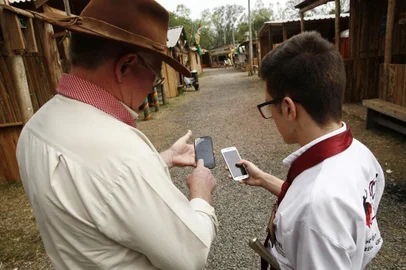  

PORTO ALEGRE, RS, BRASIL, 10-09-2017. Acampamento Farroupilha. App do Acampamento, que é um esforço do MTG para se modernizar. Sérgio Maroski (D), divulgador do app, intrui o jovem Roger Guedes, 17.   (CARLOS MACEDO/AGÊNCIA RBS)