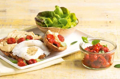 Salada de folhas com pão, homus, tomates assados e ovos pochê