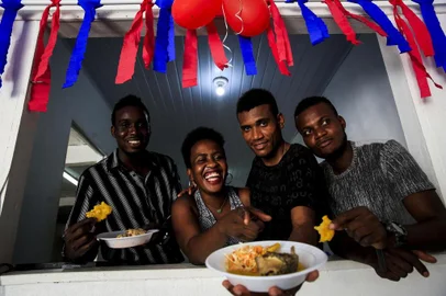 PORTO ALEGRE, RS, BRASIL, 30-12-2017: Os haitianos Esteevy Mc Fleury Joseph, Roselaure Michel, Guetty Dorcelian e Oles Blanc. Um grupo de imigrantes se reúne em uma casa de festas na zona norte de Porto Alegre para preparar a celebração de Ano Novo. Eles cozinham pratos típicos do país e o espaço recebe decoração nas cores das bandeiras do Haiti e do Brasil. (Foto: Mateus Bruxel / Agência RBS)