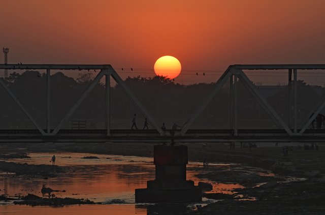 Indianos atravessam uma ponte ferroviária quando o sol se põe no horizonte pela última vez este ano em Siliguri. Indianos atravessam uma ponte ferroviária quando o sol se põe no horizonte pela última vez este ano em Siliguri.