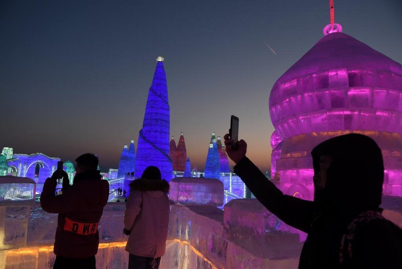 People visit the Harbin Ice and Snow World, part of the annual Harbin Ice and Snow Sculpture Festival in Harbin in Chinas northeast Heilongjiang province on January 4, 2018.The festival, which attracts hundreds of thousands of visitors annually, officially opens on January 5. / AFP PHOTO / GREG BAKER