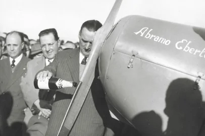 Inauguração do Aeroclube de Caxias do Sul. Da inauguração participou o empresário Assis Chateaubriand. Na foto vemos o prefeito Dante Marcucci batizando com champanhe o avião do empresário Abramo Eberle. Ao fundo, Júlio João Eberle e o ministro da aeronáutica Joaquim Pedro Salgado Filho.