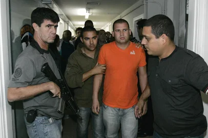  Luiz Henrique Ferreira Romão (c), o Macarrão, é transferido para a Divisão de Homicídios, na Barra da Tijuca, zona oeste do Rio de Janeiro, nesta quarta-feira. O goleiro e o amigo dele, Luiz Henrique Ferreira Romão, o Macarrão, entregaram-se nesta tarde (7) na sede da Polinter. Ele estava sendo procurado pela Justiça por suspeita de envolvimento no sumiço de Eliza Samudio, de 25 anos, com quem teve um relacionamento extraconjugal. Ela desapareceu no início do mês de junho. Os dois e ainda o adolescente J., primo de Bruno, que prestou depoimento na terça na delegacia, foram indiciados pela polícia pelo sequestro da ex-amante do goleiro, Eliza Samudio, de 25 anos, desaparecida desde 4 de junho. 07/07/2010 - Foto: ALEXANDRE BRUM/AGÊNCIA O DIA/AE