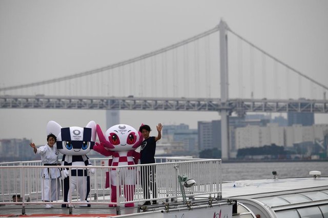 Tokyo 2020 Olympics Games mascots Miraitowa (2nd L) and Someity (2nd R) wave from a boat during a parade in front of the Rainbow bridge with karate practitioner Kiyo Shimizu (L) and para athlete Hajimu Ashida (R) in Tokyo on July 22, 2018.Japanese organisers formally introduced their doe-eyed 2020 Olympic mascots to the world on July 22, christening them with superhero names that could provide a tongue-twisting challenge to some. / AFP PHOTO / POOL / Toshifumi KITAMURA