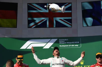 Winner Mercedes British driver Lewis Hamilton (C) celebrates with his trophy on the podium beside second placed Ferraris German driver Sebastian Vettel (L) and third placed Ferraris Finnish driver Kimi Raikkonen after the Formula One Hungarian Grand Prix at the Hungaroring circuit in Mogyorod near Budapest, Hungary, on July 29, 2018. / AFP PHOTO / ATTILA KISBENEDEK