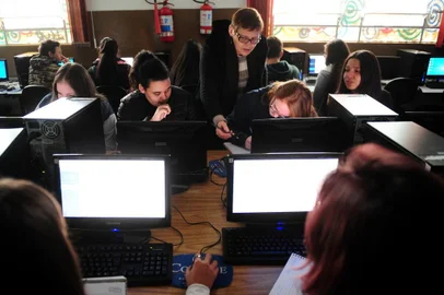  CAXIAS DO SUL, RS, BRASIL, 15/08/2018. Escola Municipal Prefeito Luciano Corsetti, em Caxias do Sul, é a primeira da rede pública no país a receber a certificação de escola digital segura, em função de práticas de segurança da internet. Na foto, de frente, Aniéle Da Silva Machado, 14 anos, Rhainara Melo da Silva, 15 anos, a professora de matemática Inês Maria Pozzer Pedroni, Rayssa Parizotto, 14 anos e Camille Santos, 14 anos, alunas do 9º ano em aula de matemática no laboratório de informática. (Diogo Sallaberry/Agência RBS)
