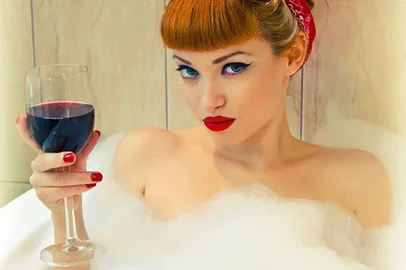 Pin-up tomando vinho tinto em banheira com espumaImportação Donnahttp://revistadonna.cli
