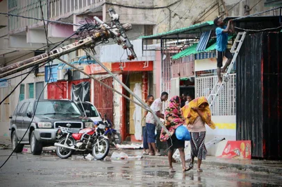 Residents are seen protecting themselves by the rain in the aftermath of the passage of the cyclone Idai in Beira, Mozambique, on March 17, 2019. - More than 120 people have died and many more are missing in Mozambique and neighbouring Zimbabwe on March 17, 2019 after tropical cyclone Idai barrelled across the southern African nations with flash floods and ferocious winds. (Photo by ADRIEN BARBIER / AFP)