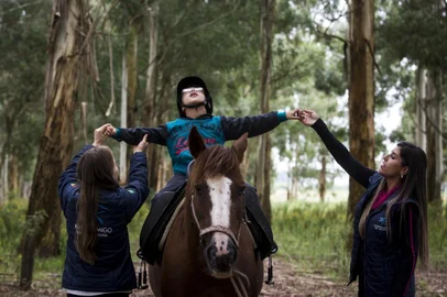 VACARIA, RS, BRASIL, 13-03-2019: RS que Inspira. A coordenadora da ONG Passo Amigo, Juliana Biazus da Silva (E), durante atendimento do menino Brayan Ostzyzek, no Parque dos Rodeios Nicanor Kramer da Luz, em Vacaria. A organização não tem fins lucrativos e oferece o serviço de equoterapia a pessoas com necessidades específicas, dificuldades escolares e problemas emocionais. (Foto: Mateus Bruxel / Agência RBS)