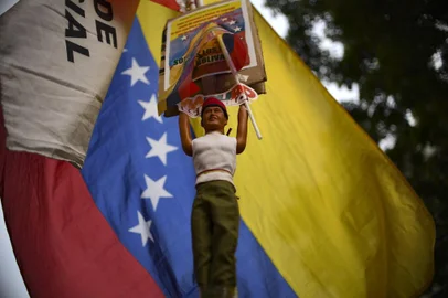 A supporters of the Venezuelas President Nicolas Maduro and who stays on a vigil in fornt of the Presidential Palace of Miraflores rises a doll representing Venezuelas late President Hugo Chavez and the national flag in Caracas, Venezuela on May 1, 2019. - Demonstrators clashed with police on the streets of the Venezuelan capital Tuesday, spurred by opposition leader Juan Guaidos call on the military to rise up against President Nicolas Maduro -- who said he had defeated an attempted coup. (Photo by YURI CORTEZ / AFP)