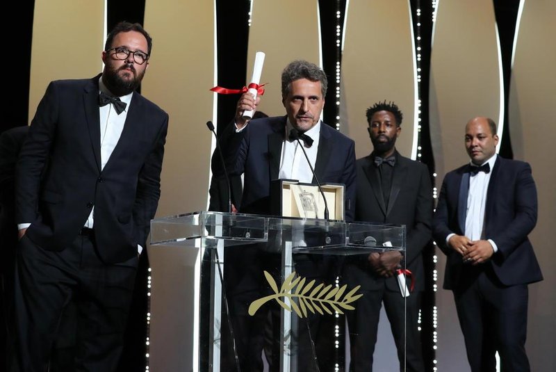 Brazilian film director Kleber Mendonca Filho (C) speaks on stage with Brazilian director Juliano Dornelles (L) after they shared the Jury Prize for their film Bacurau with French director Ladj Ly (2ndR) for his film Les Miserables on May 25, 2019 during the closing ceremony of the 72nd edition of the Cannes Film Festival in Cannes, southern France. (Photo by Valery HACHE / AFP)