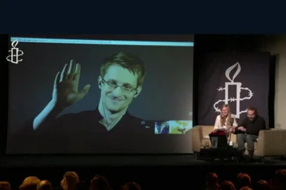 Falando por videoconferência em um ato realizado pela Anistia Internacional, em Londres, Edward Snowden qualificou de histórica a reforma que reduz os poderes da NSA. Reprodução Anistia Internacional/AFP