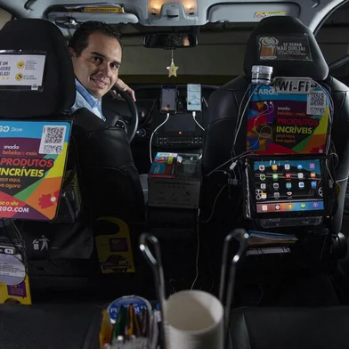 Motoristas de aplicativoSÃO PAULO, SP, 11.07.2019 - Retrato do motorista de aplicativo Pedro Madureira Neto, 39, que vende produtos dentro do seu veÃ­culo. No carro de Pedro Madureira Neto, 39, o chÃ¡ e o cafezinho sÃ£o cortesia que o motorista criado no interior faz questÃ£o de manter. Mas um cardÃ¡pio dÃ¡ outras opÃ§Ãµes: o passageiro da Uber, 99 ou Cabify pode escolher comprar chiclete, amendoim, chocolate, refrigerante, Ã¡gua de coco e atÃ© uma cerveja antes de chegar ao destino. Os preÃ§os variam de R$ 2 a R$ 9.  (Foto Danilo Verpa/Folhapress)