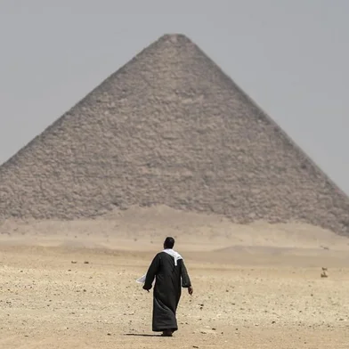 A man walks next to the Red Pyramid, in Dahshur, some 30 kilometres (20 miles) south of Cairo, on July 13, 2019. - Egyptian archaeologists unveiled Saturday several sarcophagi with some containing well-preserved mummies, along with the remains of an ancient wall dating to the Middle Kingdom nearly 4,000 years ago. The finds were made during excavation work in the ancient royal necropolis of Dahshur on the west bank of the Nile River, south of Cairo. The area is home to some of Egypts oldest pyramids including the bent pyramid of King Sneferu, the first pharaoh of Egypts 4th dynasty. (Photo by Mohamed el-Shahed / AFP)