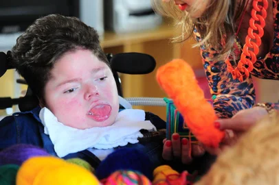 CAXIAS DO SUL, RS, BRASIL, 12/07/2019. O menino Arthur Biolchi, 14 anos, que tem síndrome de Werdinig-Hoffman, tece (escolhe as cores)  mandalas Rosa dos Ventos com o movimento dos olhos e sua história foi contada por um escritor do Mato Grosso em um site. Na foto, Arthur com a enfermeira Rosa Cappellaro Andreazza, confeccionando as mandalas. (Porthus Junior/Agência RBS)