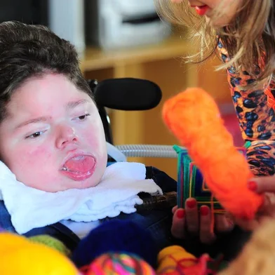 CAXIAS DO SUL, RS, BRASIL, 12/07/2019. O menino Arthur Biolchi, 14 anos, que tem síndrome de Werdinig-Hoffman, tece (escolhe as cores)  mandalas Rosa dos Ventos com o movimento dos olhos e sua história foi contada por um escritor do Mato Grosso em um site. Na foto, Arthur com a enfermeira Rosa Cappellaro Andreazza, confeccionando as mandalas. (Porthus Junior/Agência RBS)