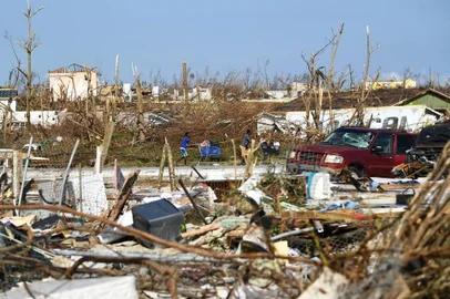 People push a shopping carts past debris in the Mudd neighbourhood in Marsh Harbor, Great Abaco, on September 7, 2019, in the aftermath of Hurricane Dorian. - Bahamians who lost everything in the devastating passage of Hurricane Dorian were scrambling Saturday to escape the worst-hit islands by sea or by air, after the historically powerful storm left at least 43 people dead with officials fearing a significantly higher toll. (Photo by Brendan Smialowski / AFP)
