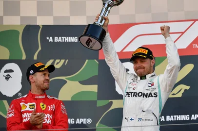 Mercedes Finnish driver Valtteri Bottas (R) raises the trophy to celebrate his victory beside second-placed Ferraris German driver Sebastian Vettel (L) on the podium after the Formula One Japanese Grand Prix in Suzuka on October 13, 2019. (Photo by TOSHIFUMI KITAMURA / AFP)