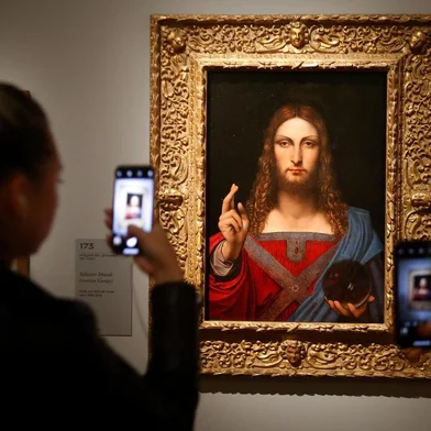 People take pictures with mobile phone at an oil painting by Leonardo da Vincis   Salvator Mundi, during the opening of the exhibition  Leonardo da Vinci , on October 22, 2019 at the Louvre museum in Paris. - Five hundred years after the death of Leonardo da Vinci, the Louvre Museum inaugurates on October 23, 2019 the largest exhibition ever set up around the work of the genius of the Renaissance, which is already announced as a popular success. (Photo by FRANCOIS GUILLOT / AFP) / RESTRICTED TO EDITORIAL USE - MANDATORY MENTION OF THE ARTIST UPON PUBLICATION - TO ILLUSTRATE THE EVENT AS SPECIFIED IN THE CAPTION