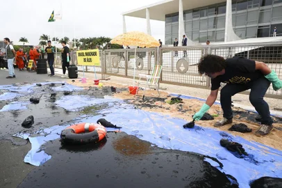  A Greenpeace activist spills fake oil during a protest in front of Planalto Palace in Brasilia, Brazil, Wednesday, October 23, 2019. - Greenpeace denounced what they call government negligence due to large blobs of oil staining more than 130 beaches in northeastern Brazil began appearing in early September and have now turned up along a 2,000km stretch of the Atlantic coastline. The source of the patches remain a mystery despite President Jair Bolsonaros assertions they came from outside the country and were possibly the work of criminals. (Photo by Sérgio Lima / AFP)Editoria: ENVLocal: BrasíliaIndexador: SERGIO LIMASecao: environmental pollutionFonte: AFPFotógrafo: STR