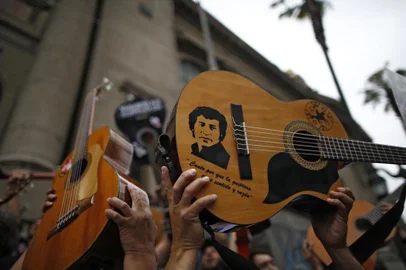 Demonstrators hold up their guitards after performing Chilean musician Victor Jaras (depicted) The right to live in peace in Santiago, on October 25, 2019, a week after violence protests started. - Demonstrations against a hike in metro ticket prices in Chiles capital exploded into violence on October 18, unleashing widening protests over living costs and social inequality. (Photo by Pablo VERA / AFP)