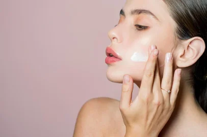 Skin cream concept. Facial care for female. Keep skin hydrated regularly moisturizing cream. Fresh healthy skin concept. Taking good care of her skin. Beautiful woman spreading cream on her faceConceito de creme para a pele. Cuidados faciais para a mulher. Mantenha a pele hidratada regularmente creme hidratante. Conceito de pele fresca e saudável. Tomando bom cuidado de sua pele. Bela mulher espalhando creme em seu rostoFonte: 265891694