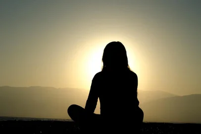 Mulher medita de frente para o sol. Saiba quais os benefícios que a meditação traz para a saúde. CADERNO VIDA. 29/04/2016.