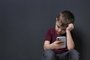  Sad little boy with mobile phone on black background, space for textFonte: 269566699