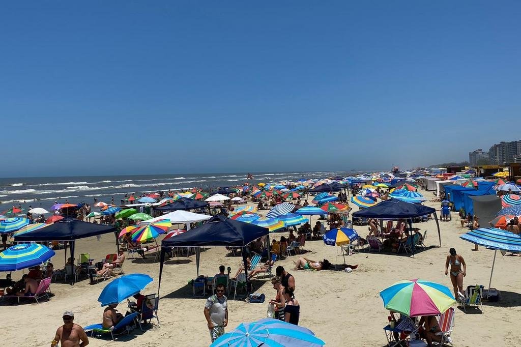 Com céu azul e praia lotada, banhistas passam o dia na beira-mar em ...