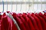  PORTO ALEGRE, RS, BRASIL, 03/09/2017- Uniforme escolar em cabides. Varias camisas vermelhas e uma cinza. Foco seletivo. Foto: stock.adobe.com / GalinaStFonte: 170171965