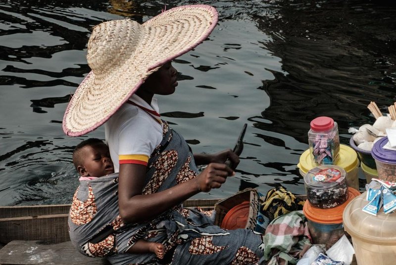 A picture taken on March 2, 2019 shows a woman selling daily items on a boat in the Makoko waterfront community in a polluted lagoon in Lagos, Africas biggest megalopolis in Nigeria. - The sprawling community began in the 19th century as a fishing village for immigrants who settled on the waters edge. As more arrived and land became rare, people started to move out onto the water. Over time, Makoko became a floating realm of perhaps a quarter of a million people, although the real number is anyones guess. (Photo by YASUYOSHI CHIBA / AFP)<!-- NICAID(14392682) -->
