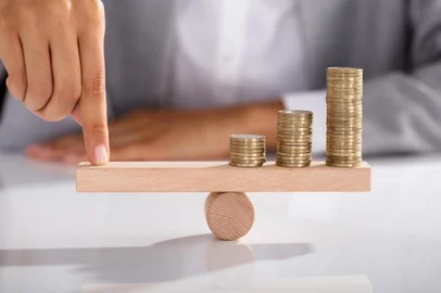  Close-up Of Businessperson's Finger Balancing Stacked Of Coins On Wooden SeesawIndexador: Andrey PopovFonte: 190662072<!-- NICAID(14394281) -->